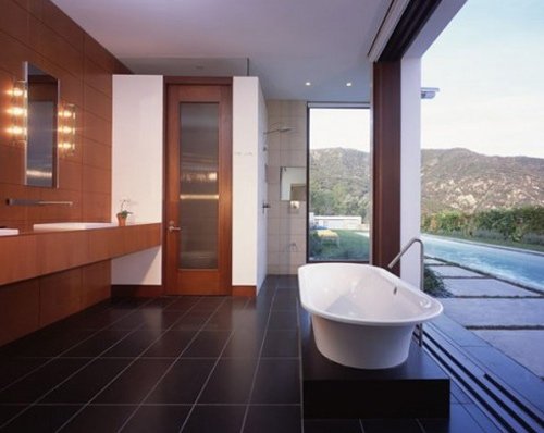 mid-century-modern-bathroom-design-with-open-plan-and-stunning-white-tub-on-black-tile-floor-before-long-wooden-vanity-idea-with-frameless-wall-mirror-and-wooden-backsplash