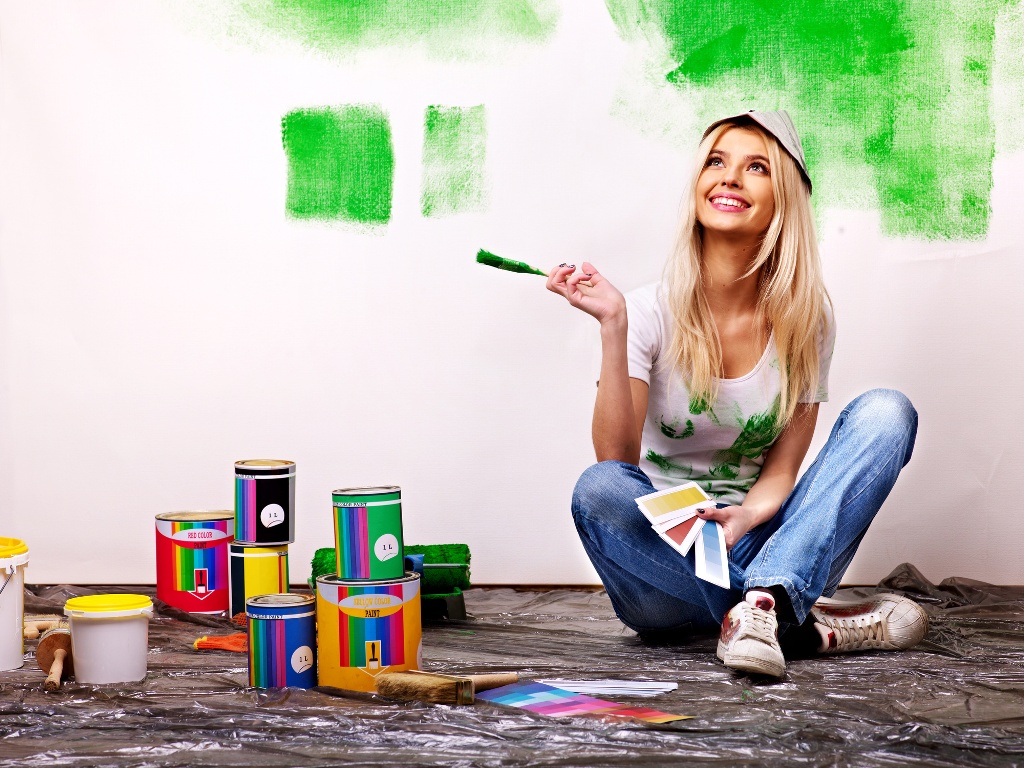 Happy woman paint wall at home.